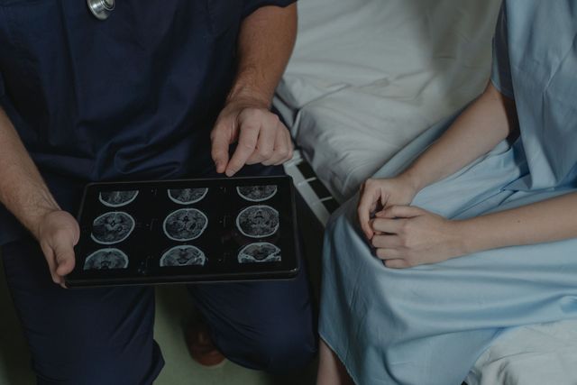 Doctor showing brain scans to a seated patient in a clinic