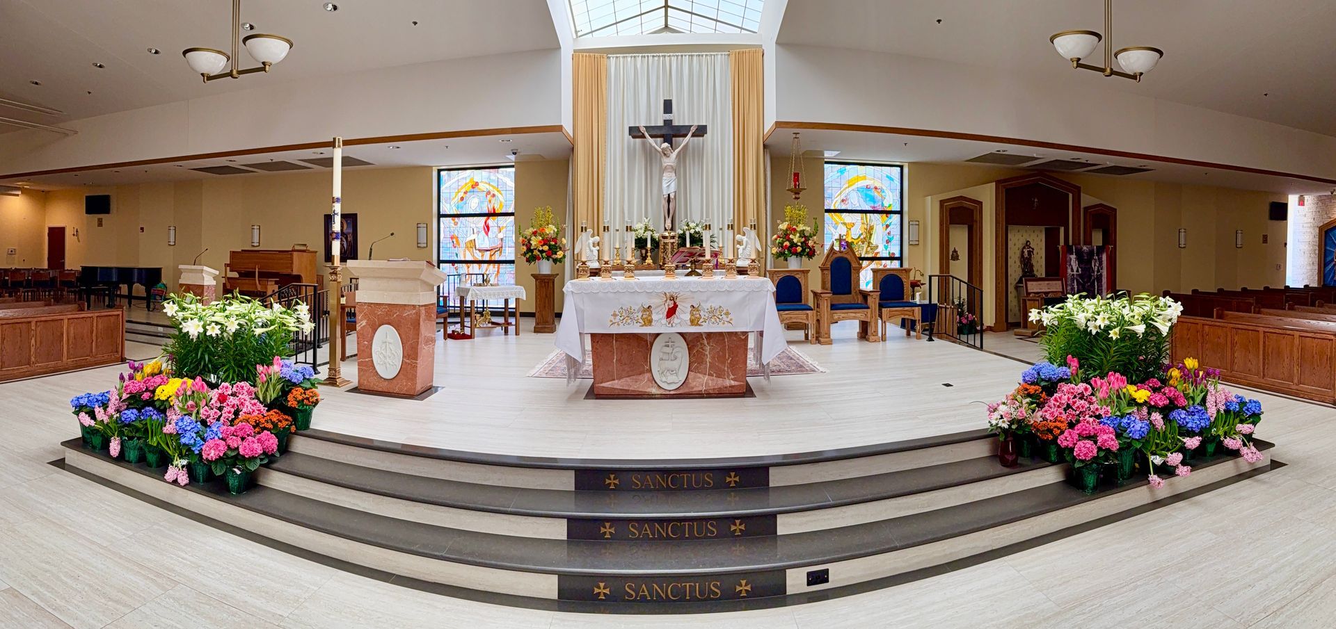 Decorated church altar with flowers, candles, and wooden lectern in a bright sanctuary