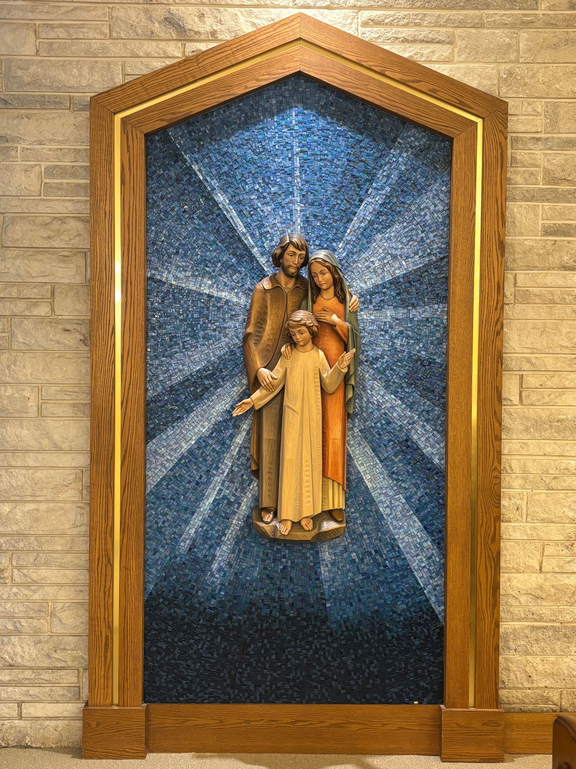 Religious mosaic of the Virgin Mary holding baby Jesus in a gold-framed niche with blue background