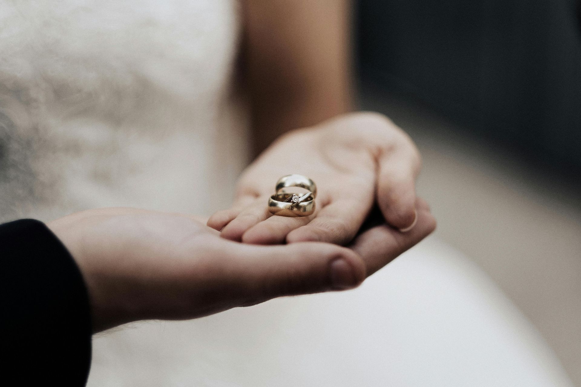 Hands gently holding a gold ring with a clear gemstone