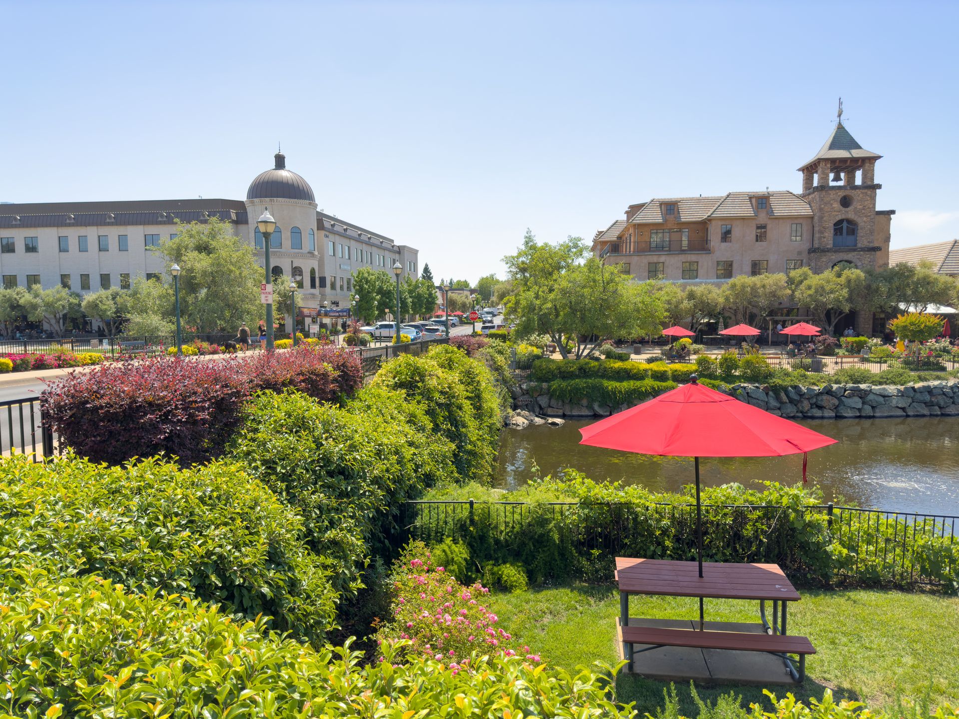 A picnic table with a red umbrella in a park