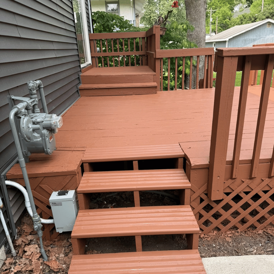Backyard wooden deck with three steps, railing, and gas meter beside a house