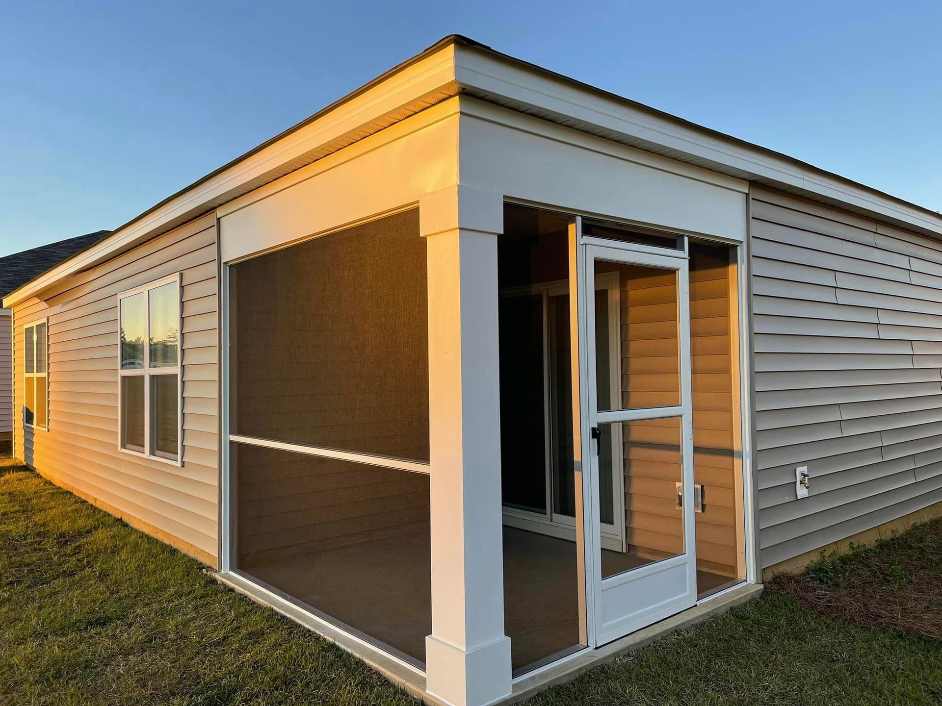 A small house with a screened in porch and sliding glass doors.