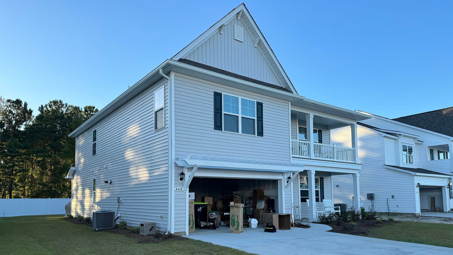 A white truck is parked in a garage next to a white house with new gutters in Loris SC