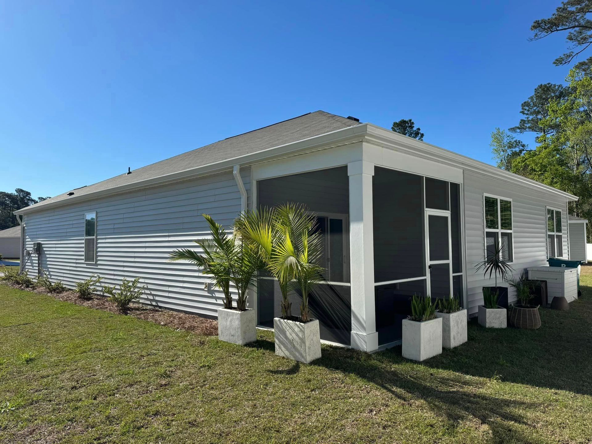A white house with a screened in porch and planters in front of it in Mullins