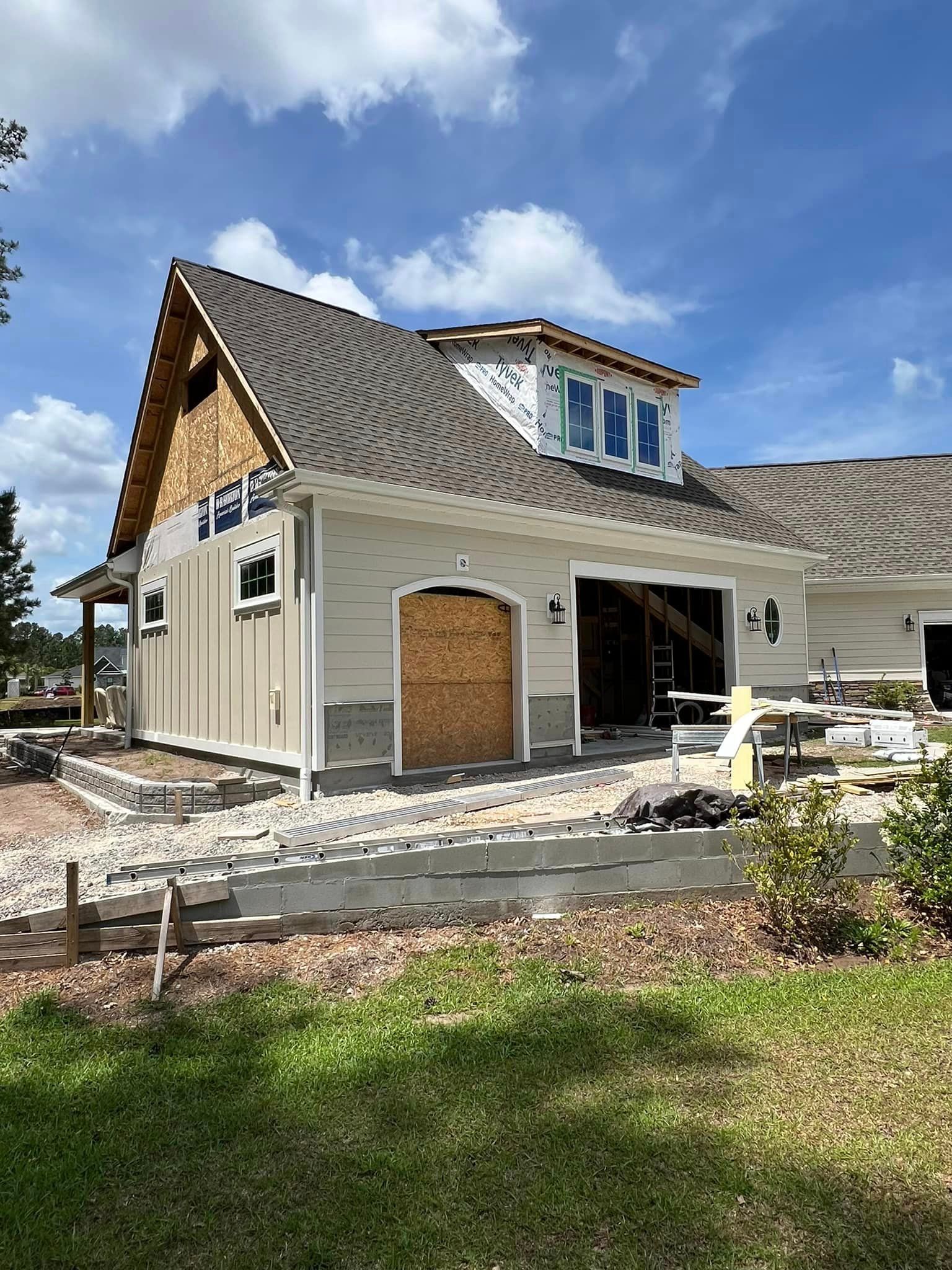 The side of a house with a garage, a blue sky in the background and a quality gutter installation in Coastal Carolina