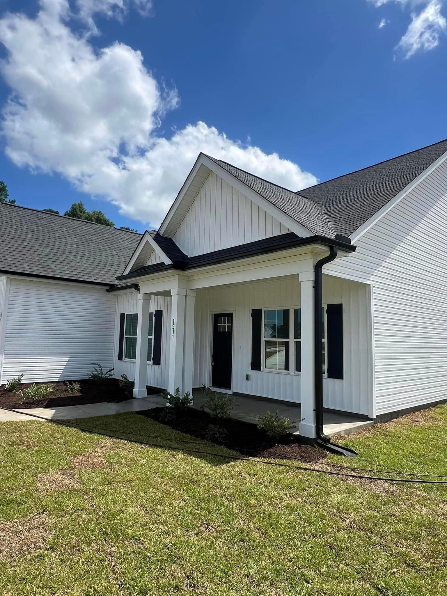 A white house with black shutters, a porch and a gutter leaf guard in Johnsonville