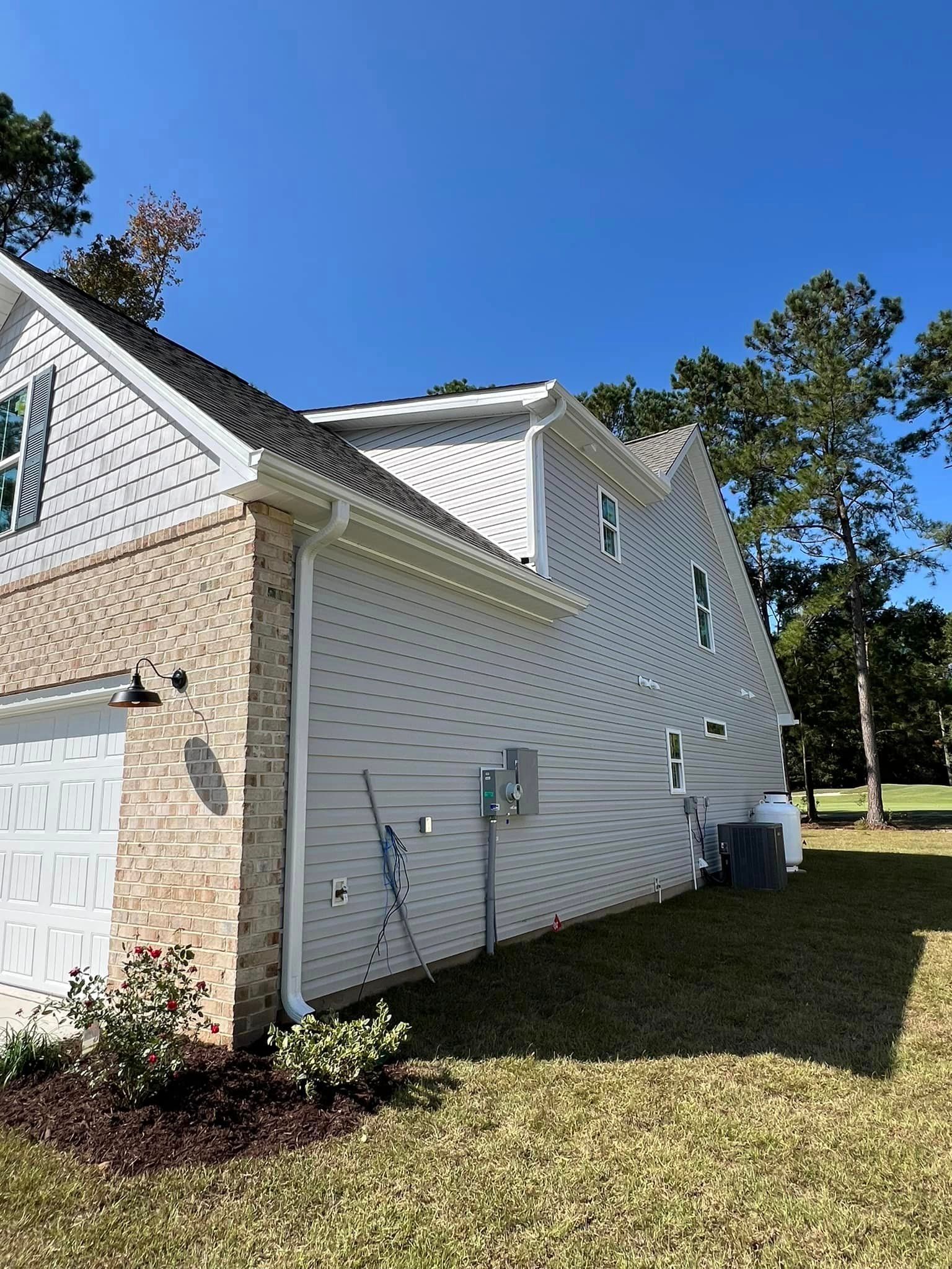 The side of a house with a garage and newly installed gutter in Galivants Ferry