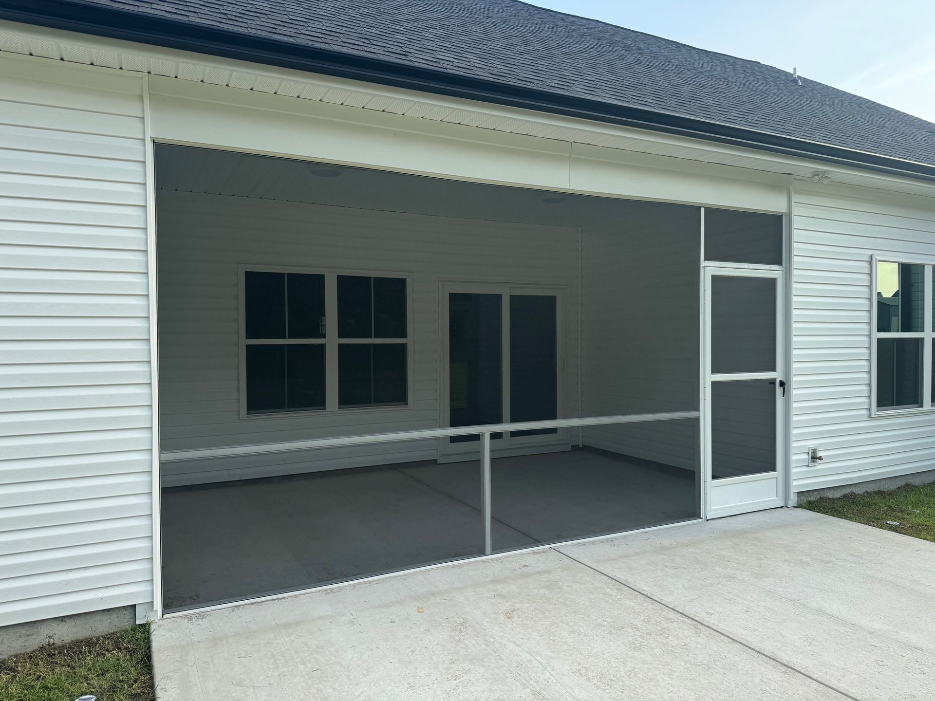 A screened in porch with a white house in the background