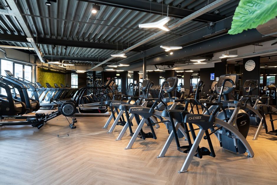 Een grote sportschool vol met fitnessapparatuur.