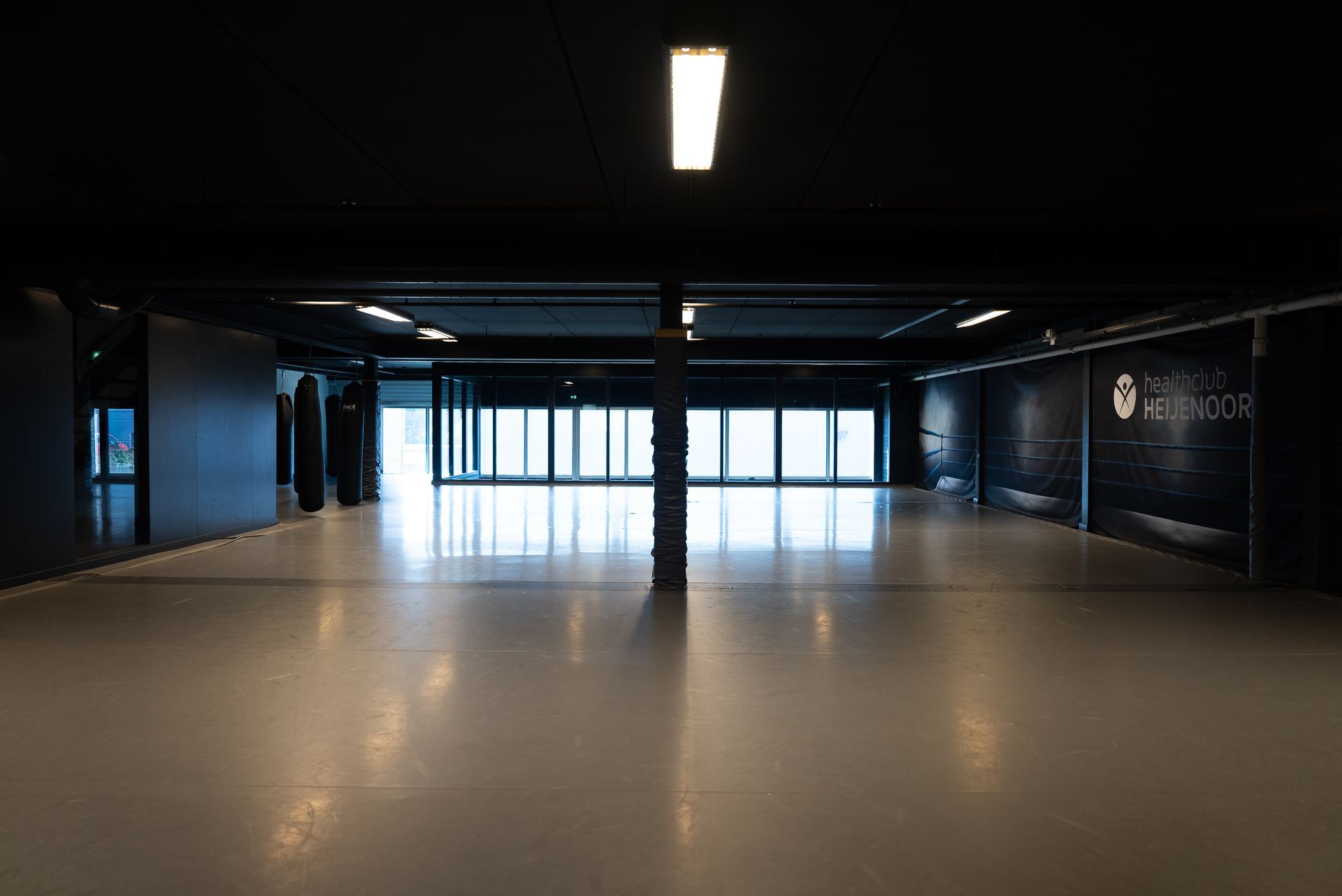 Een grote lege kamer met veel ramen en een licht aan het plafond.