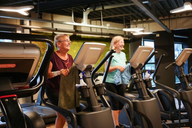Twee vrouwen staan naast elkaar op een loopband in een sportschool.