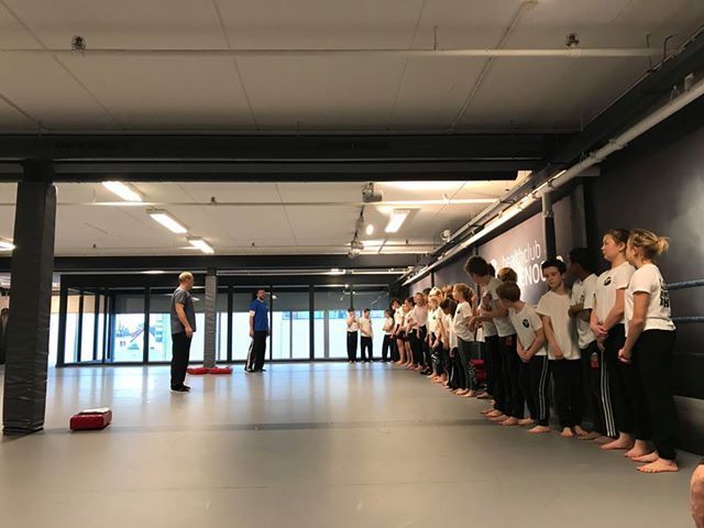 Een groep mensen staat in een rij in een gymzaal.