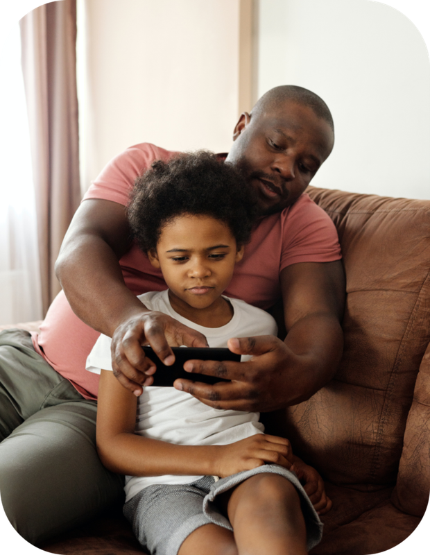 Adult and child sitting on a couch, looking at a smartphone together