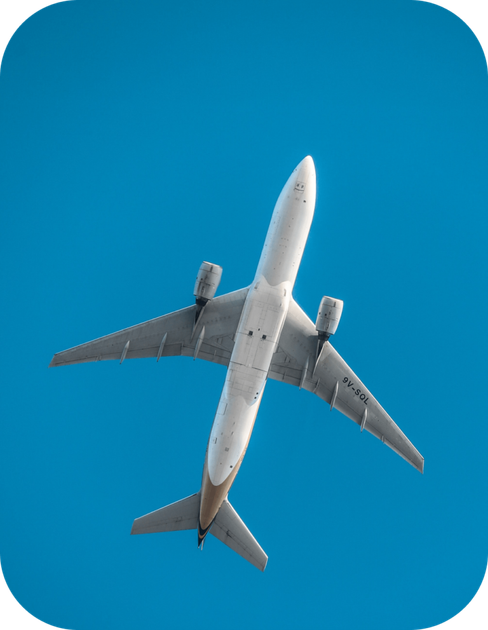 Commercial airplane flying overhead against a bright blue sky