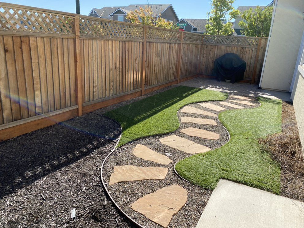 A backyard with a wooden fence and a stone walkway.