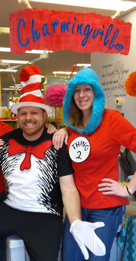 Two people in Dr. Seuss-style costumes standing under a “Charmingville” sign at an indoor event.
