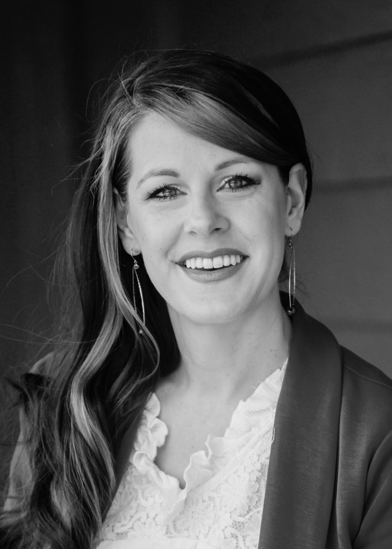 A woman with long hair is smiling in a black and white photo.
