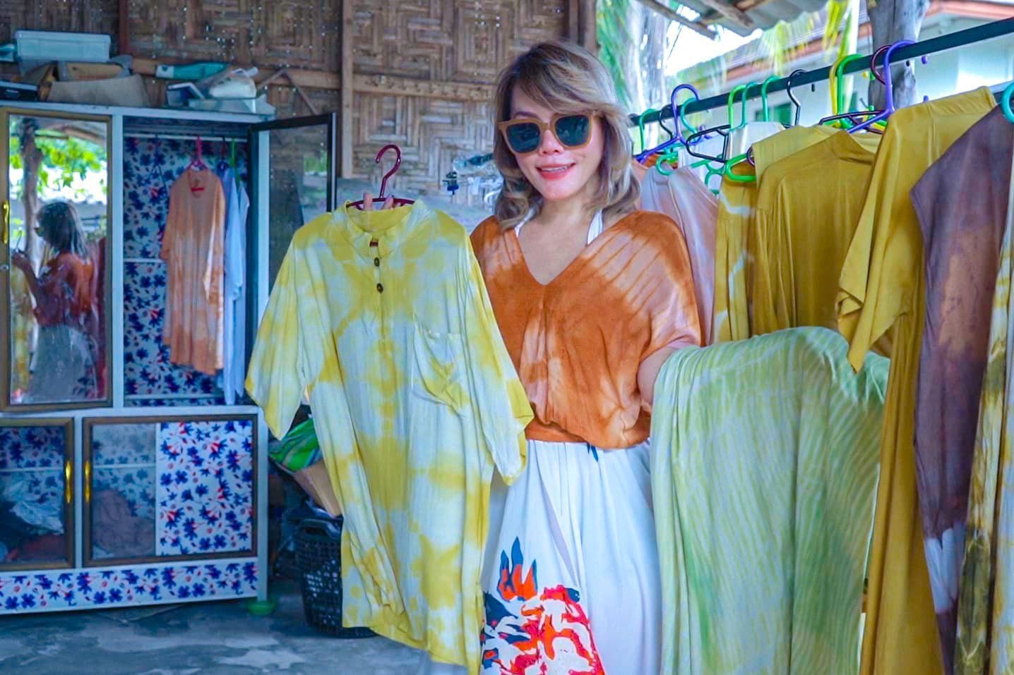 A woman is holding a bunch of clothes in a store.
