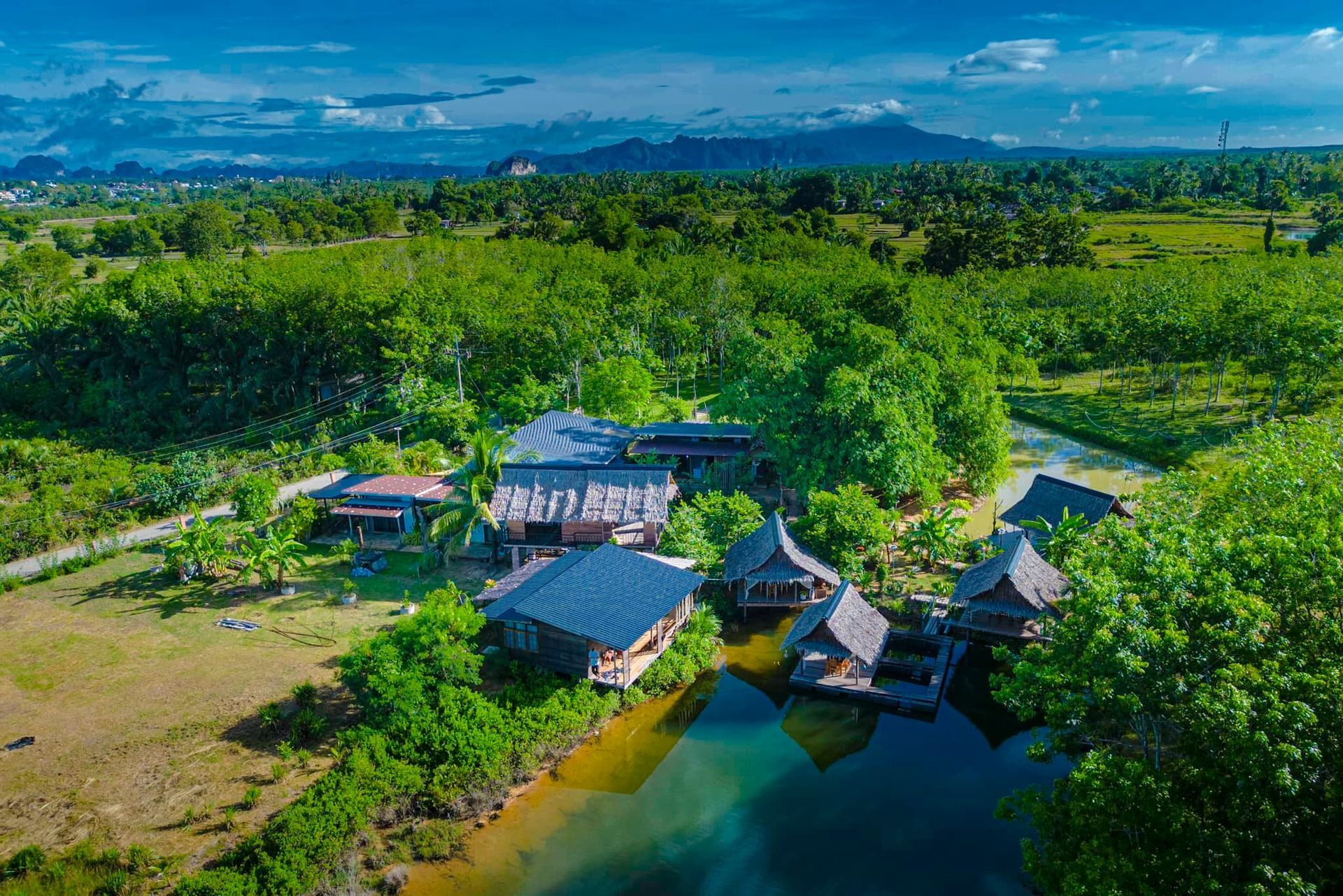 An aerial view of a tropical resort surrounded by trees and a lake.