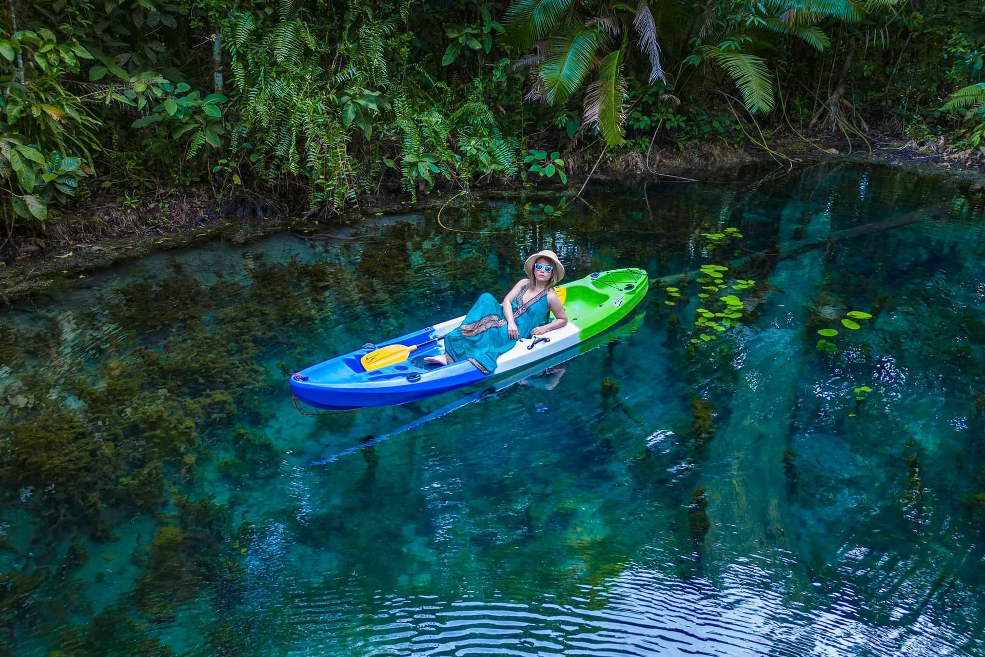 A woman is riding a kayak on a river.