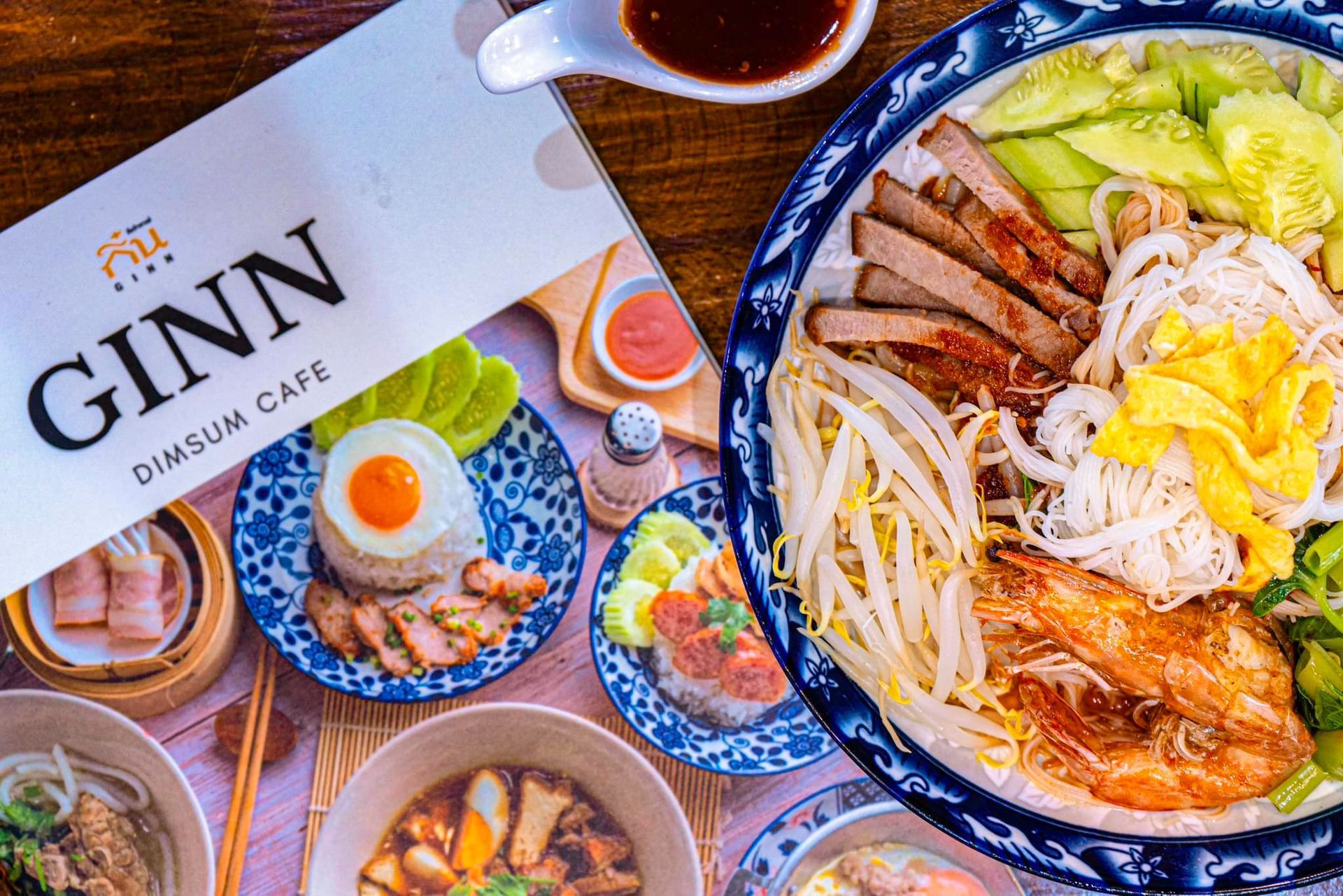 A table topped with plates of food and a menu for ginn dimsum cafe.