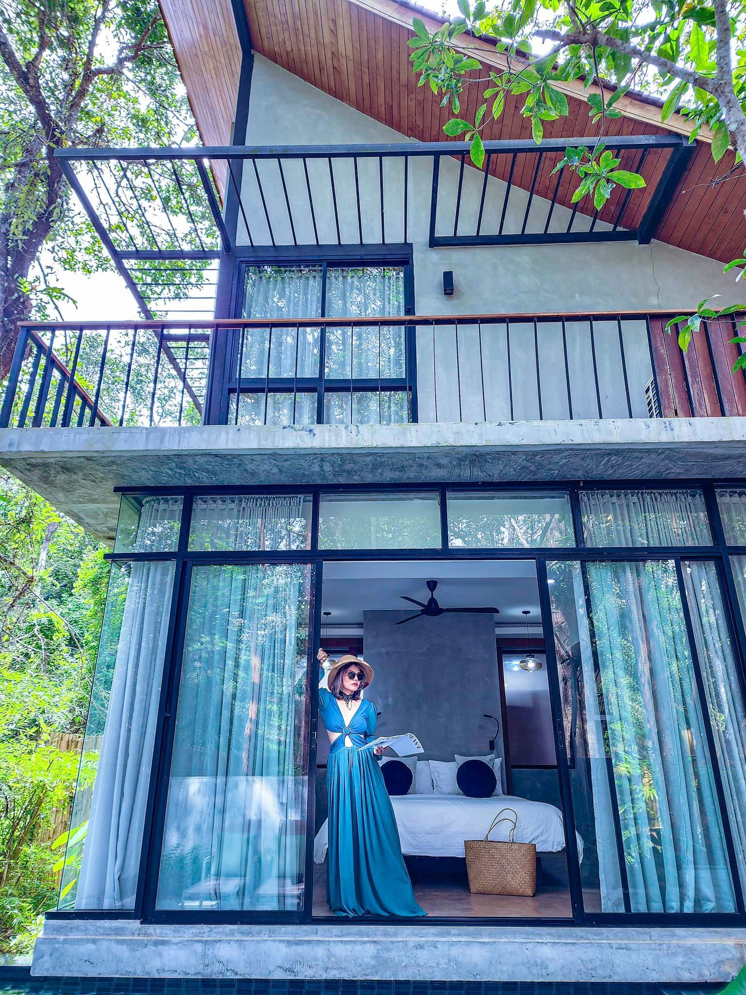 A woman in a blue dress is standing on the balcony of a house.