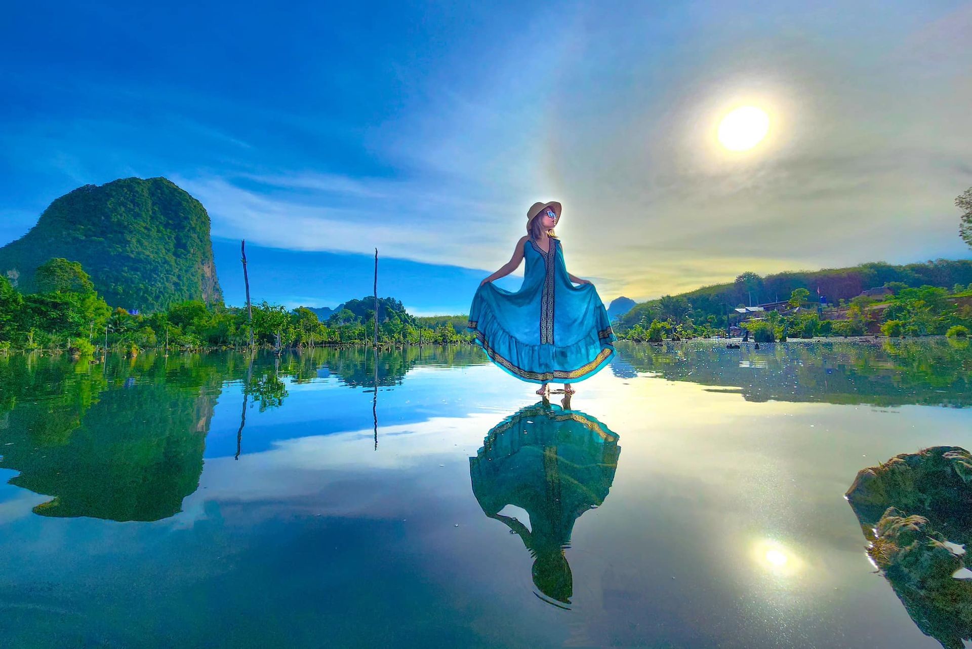 A woman in a blue dress is standing in the middle of a lake.