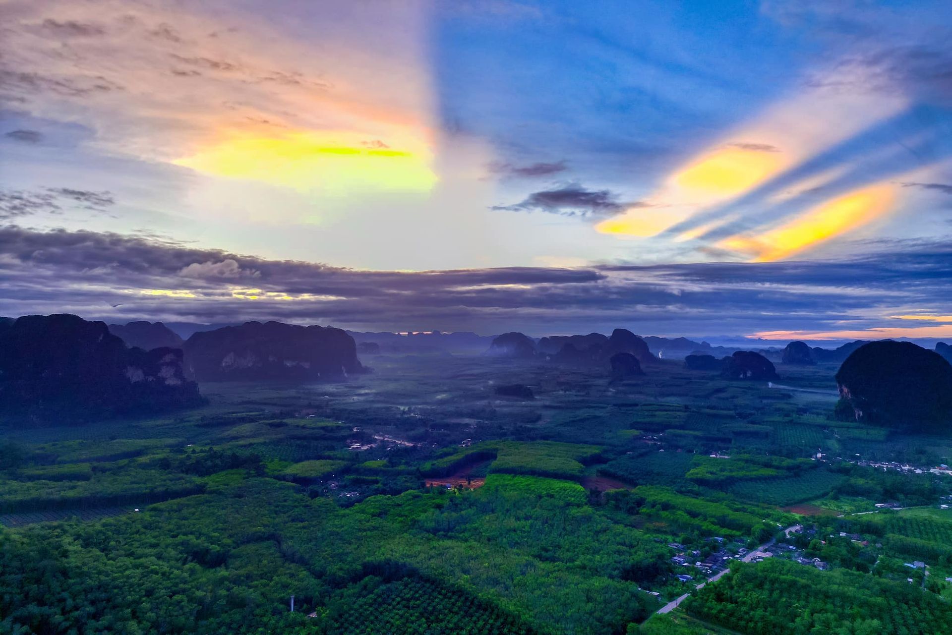 An aerial view of a lush green valley at sunset.