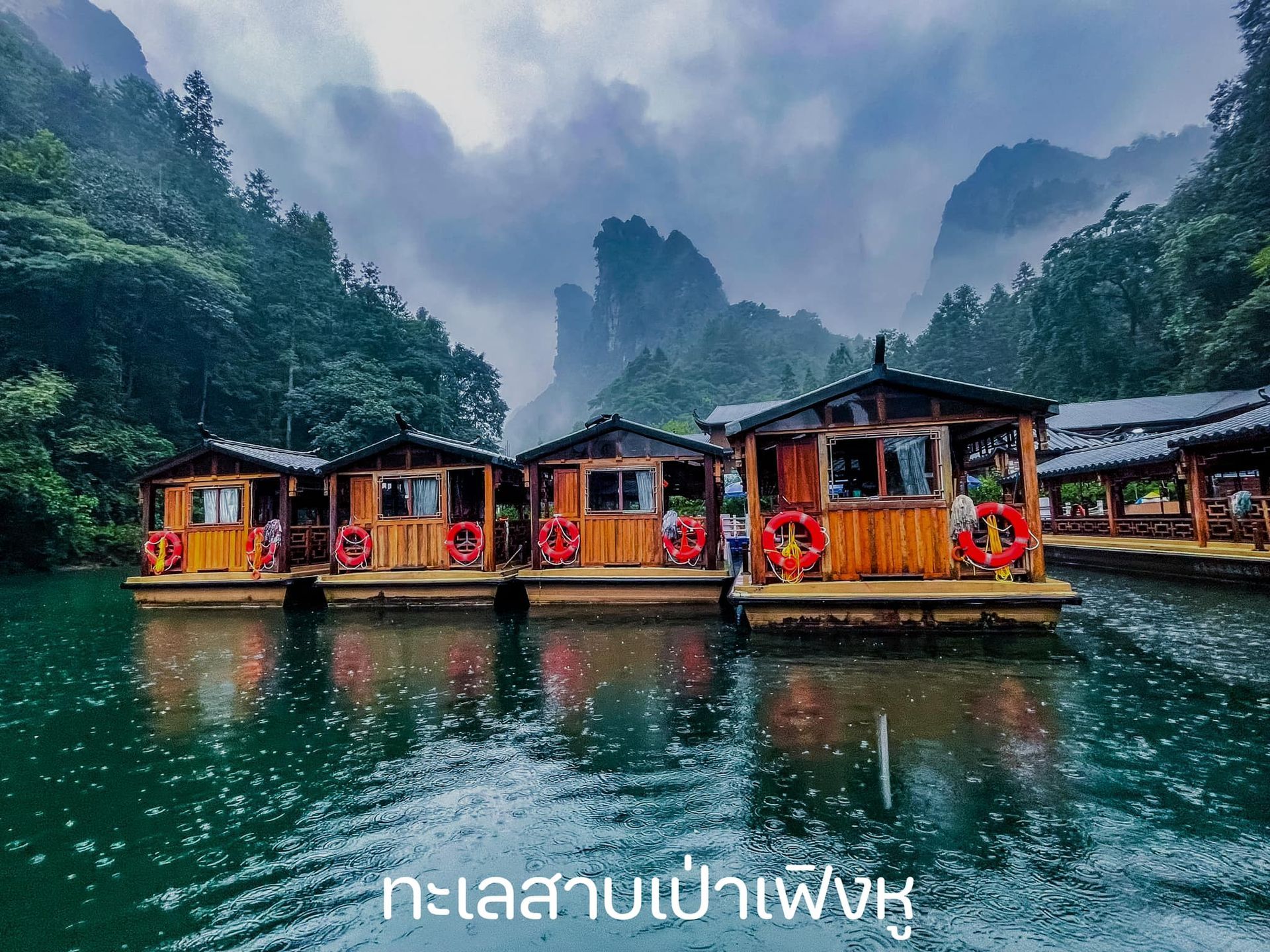 A row of floating houses on a lake with mountains in the background
