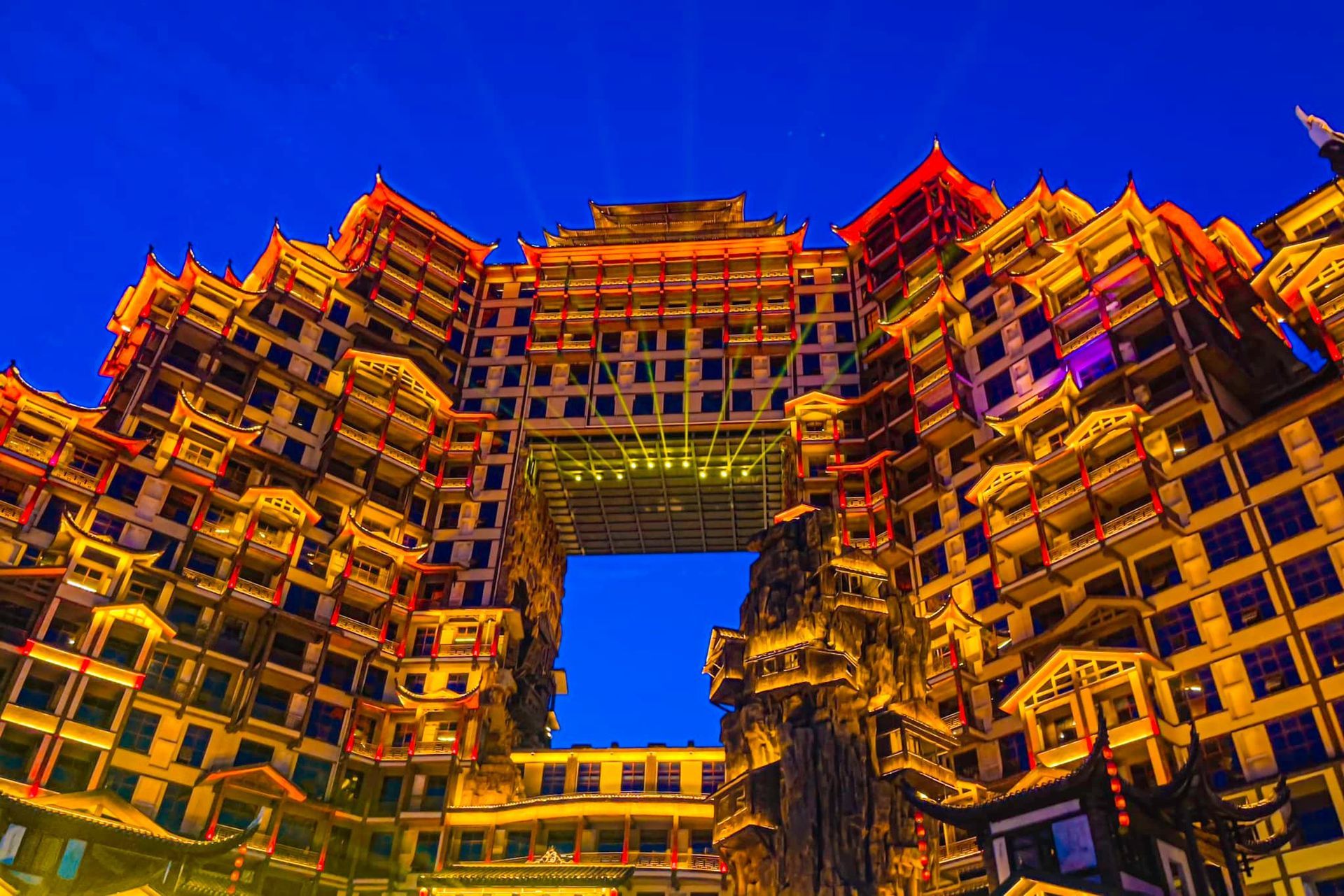 A large building with a blue sky in the background is lit up at night.