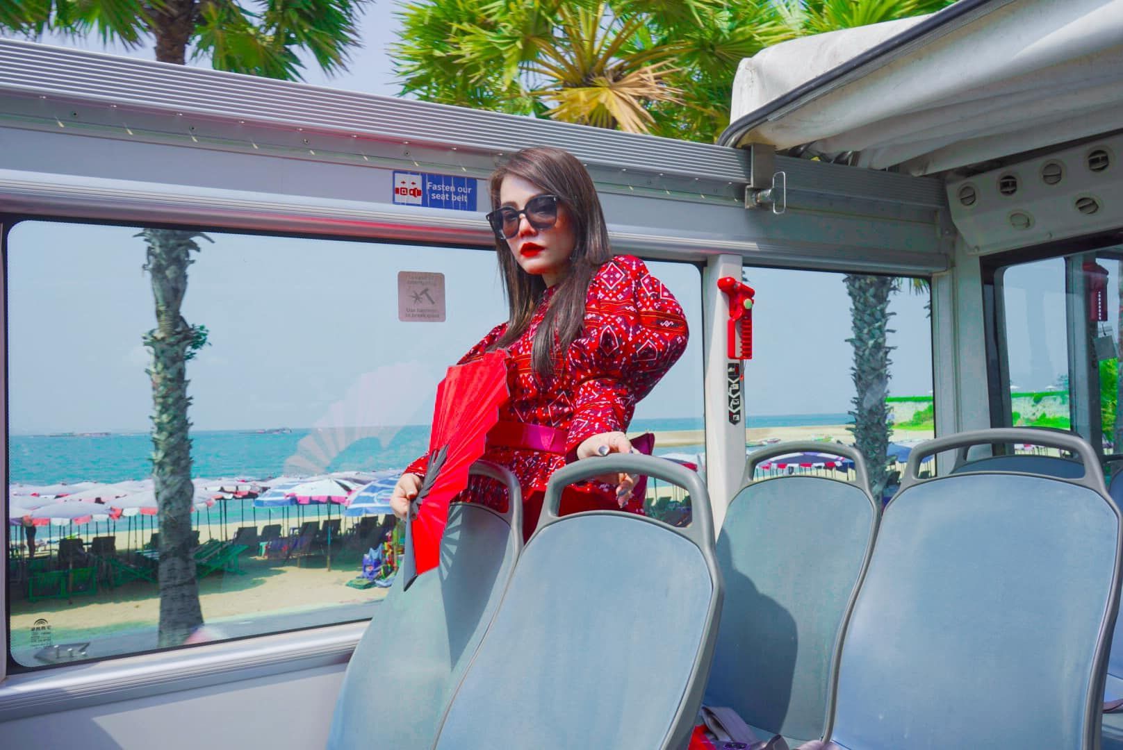 A woman in a red dress is sitting on a bus.
