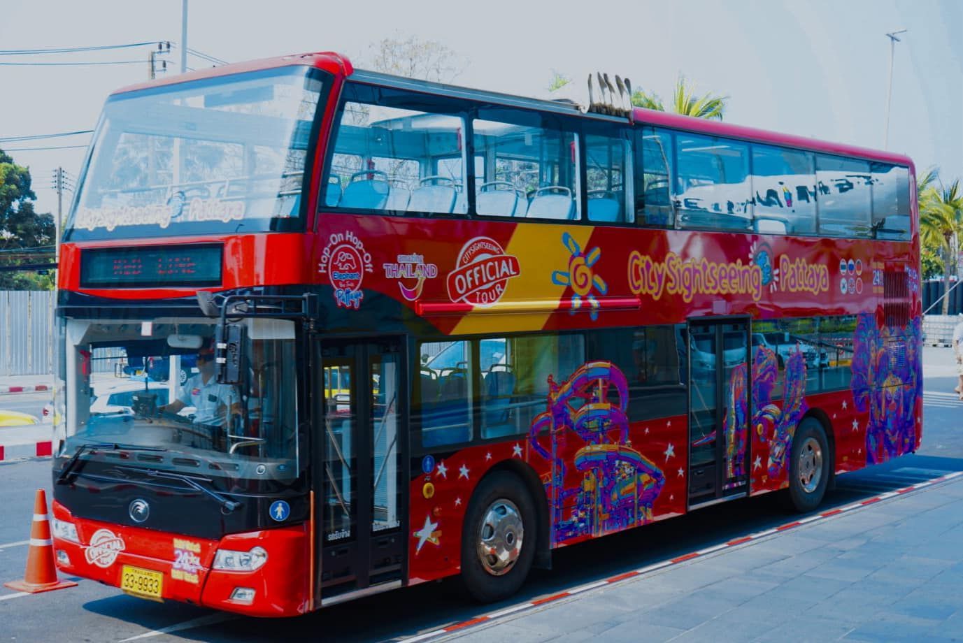 A red double decker bus is parked on the side of the road