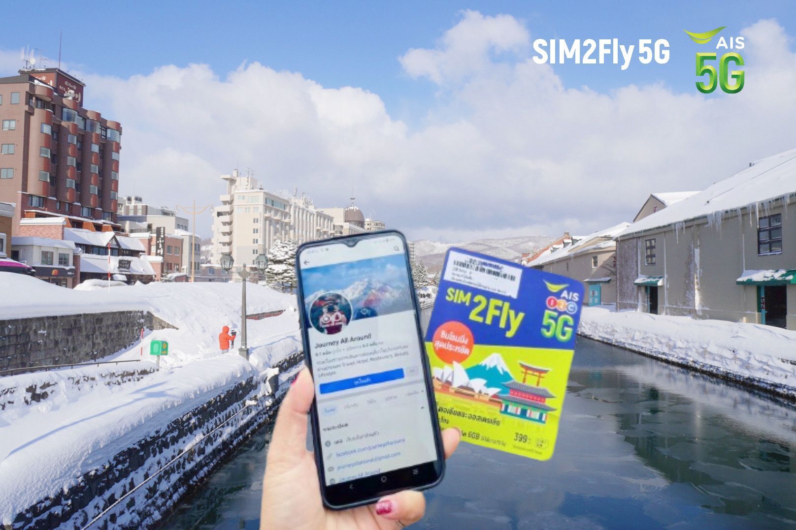 A person is holding a cell phone and a sim card in front of a snowy city.