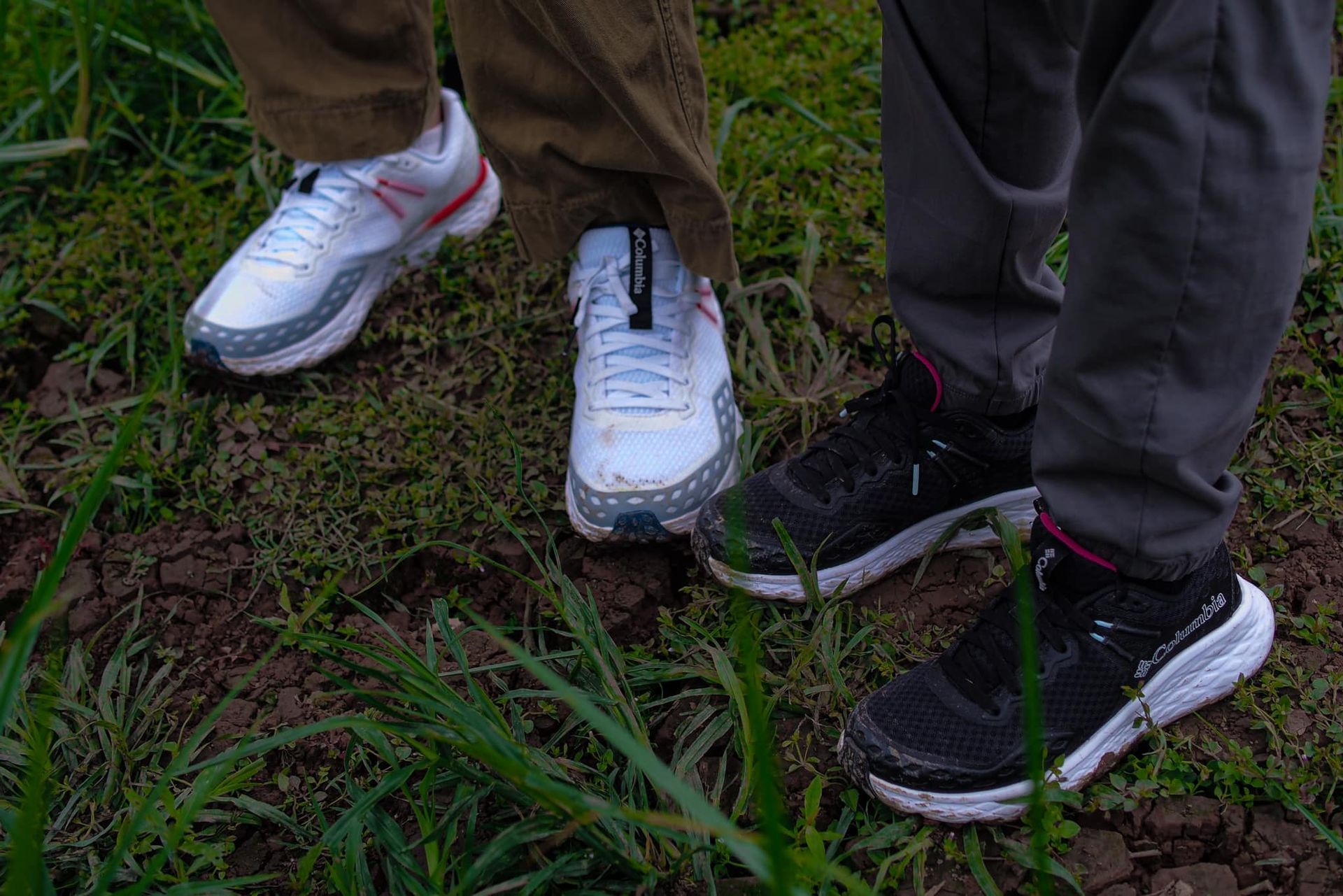 A couple of people standing next to each other in the grass wearing sneakers.