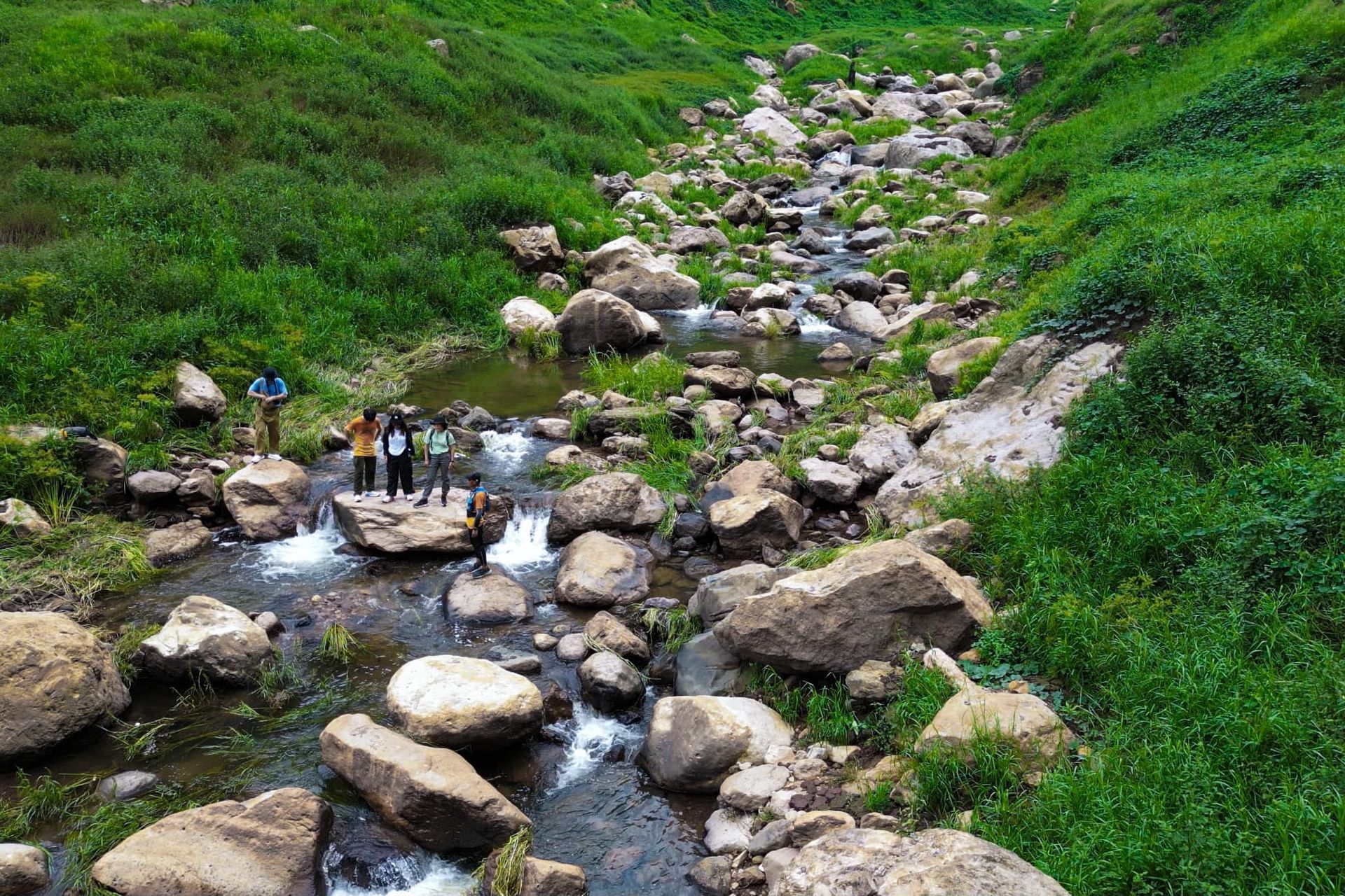 A group of people are standing on top of a rocky stream.