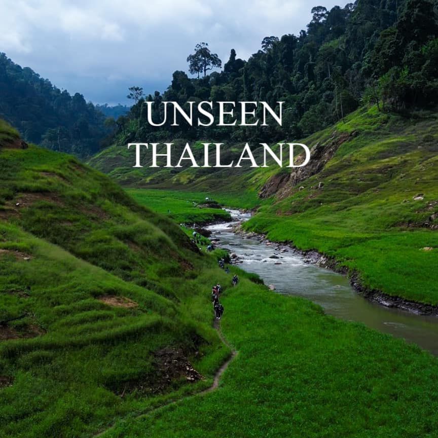 A river runs through a lush green valley in thailand.