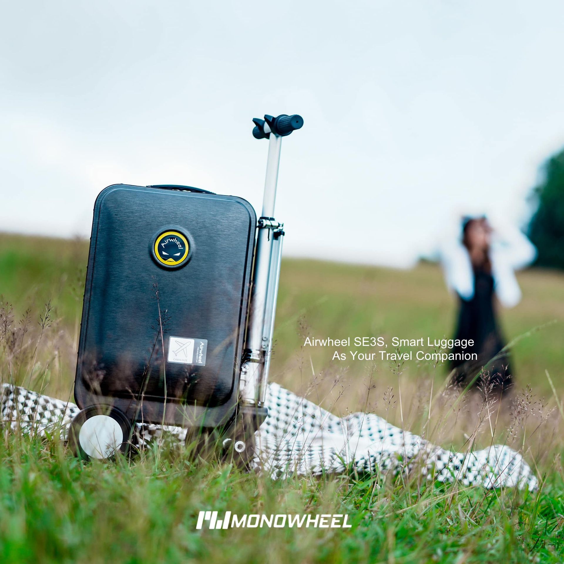 A black suitcase is laying on a blanket in the grass