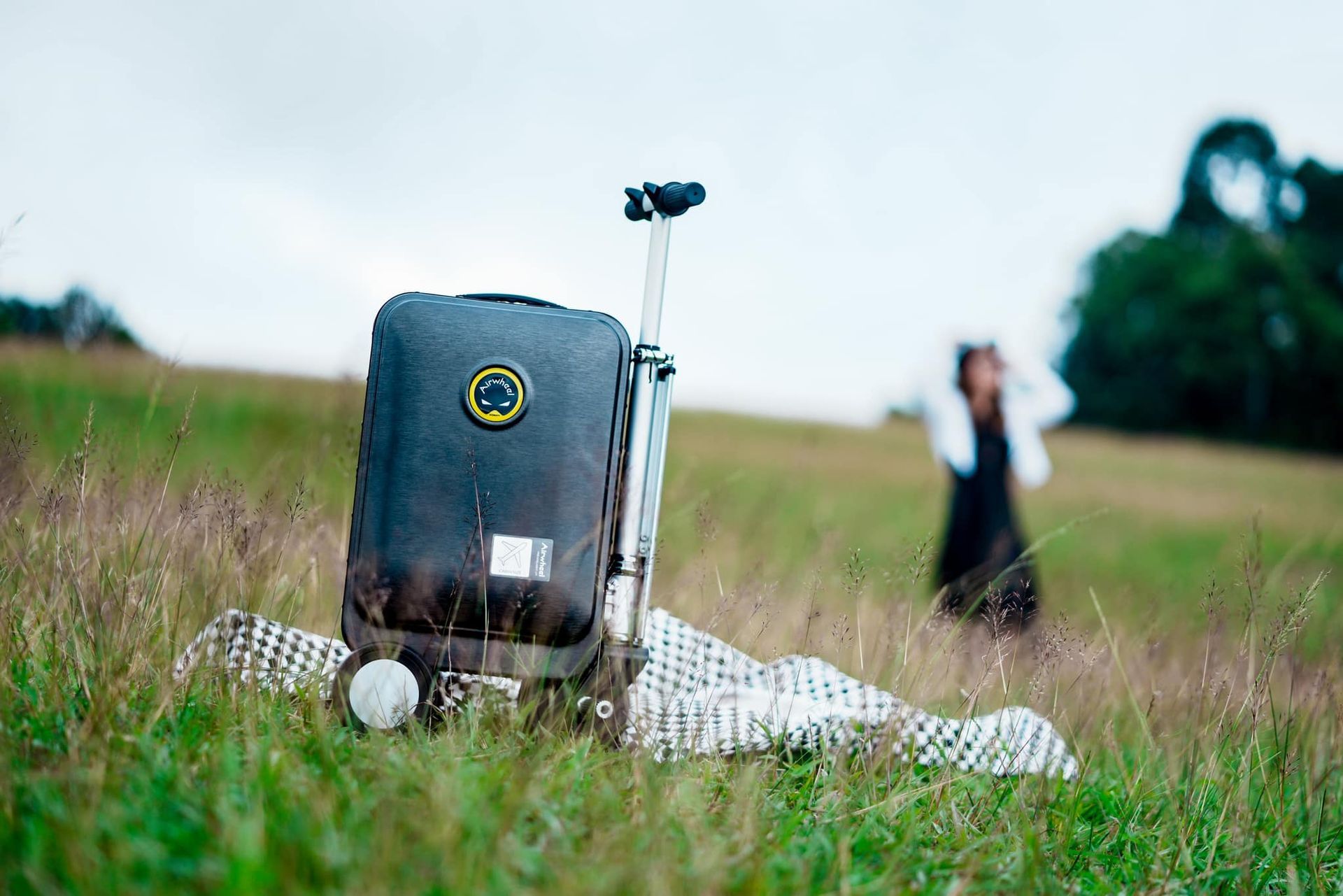 A suitcase is sitting on top of a blanket in a field.