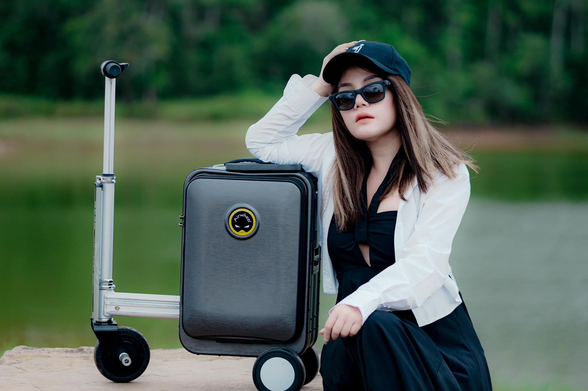 A woman is sitting next to a suitcase on a dock.