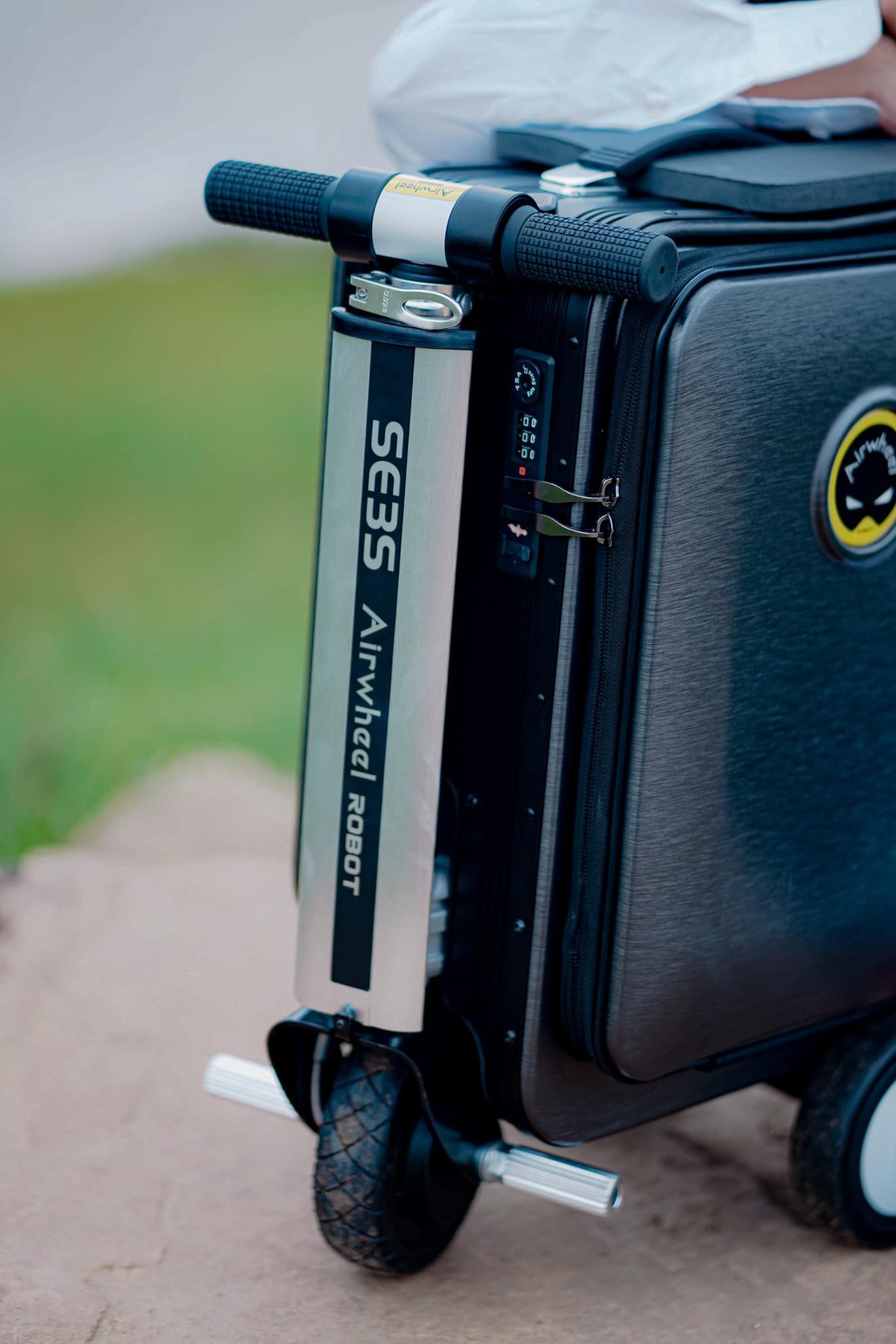A person is pushing a suitcase on wheels.