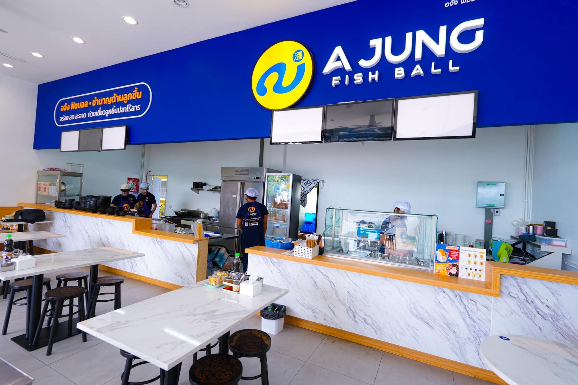 A restaurant with tables and chairs and a sign that says ajung fish ball.