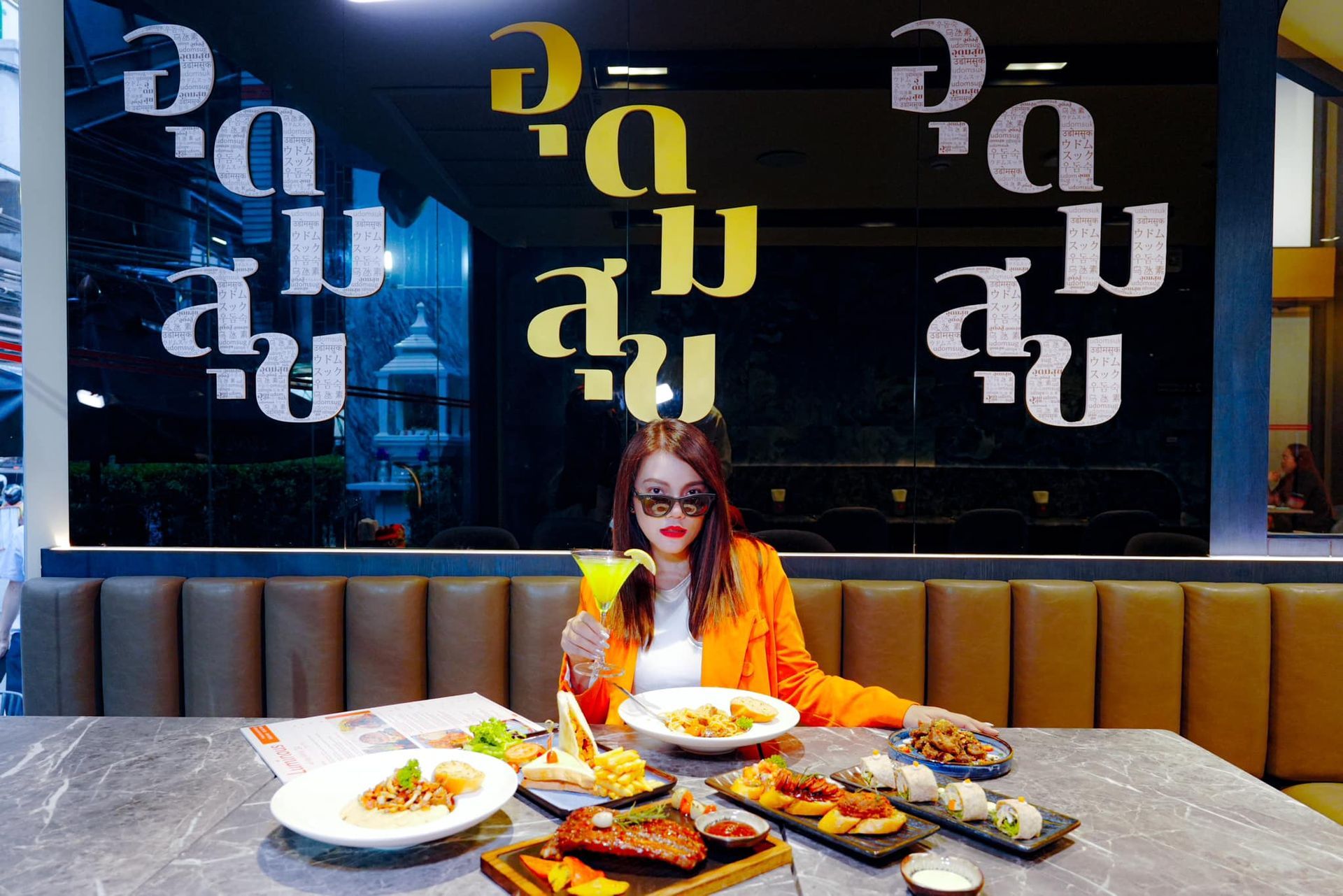 A woman is sitting at a table with plates of food.