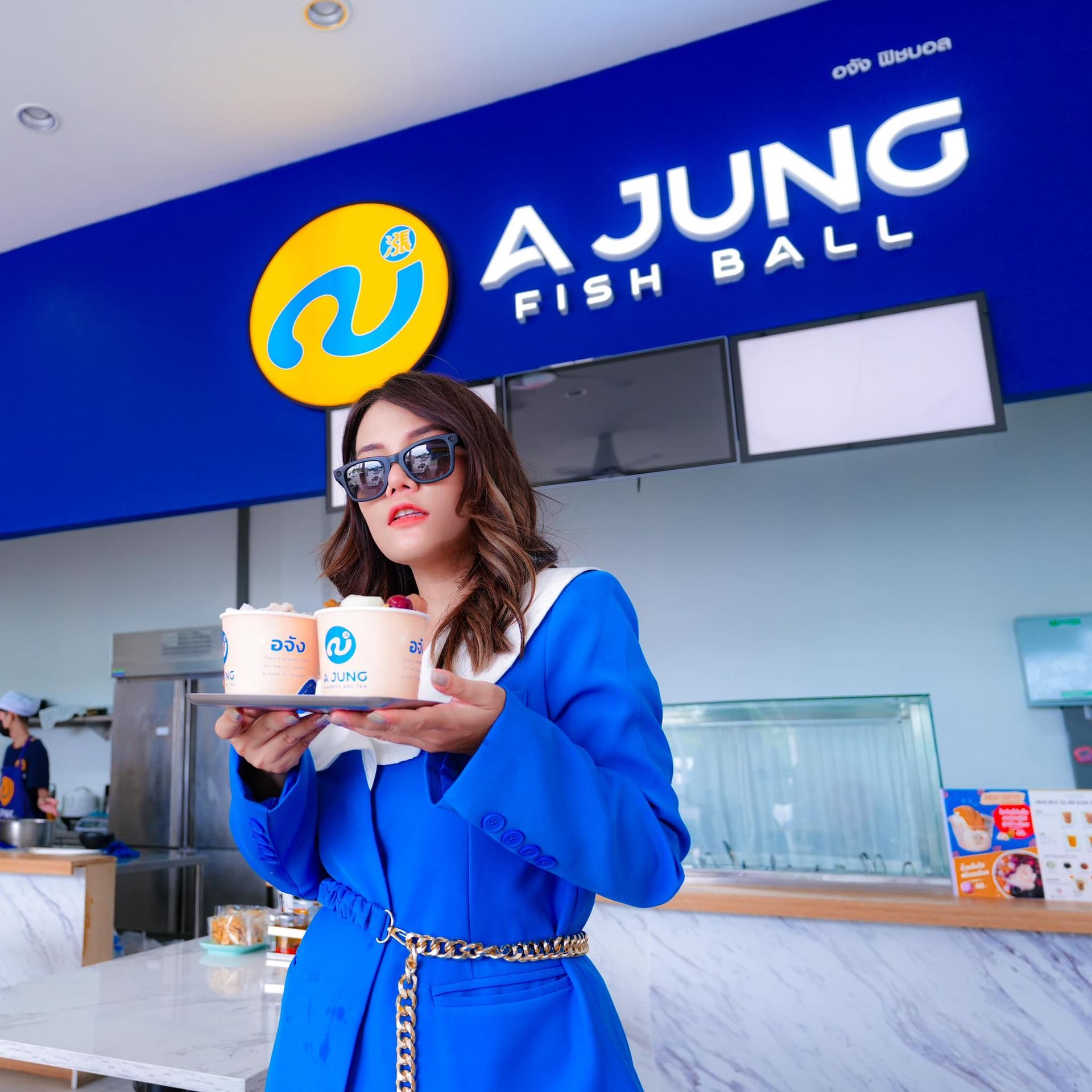 A woman is standing in front of a sign that says a jung fish ball