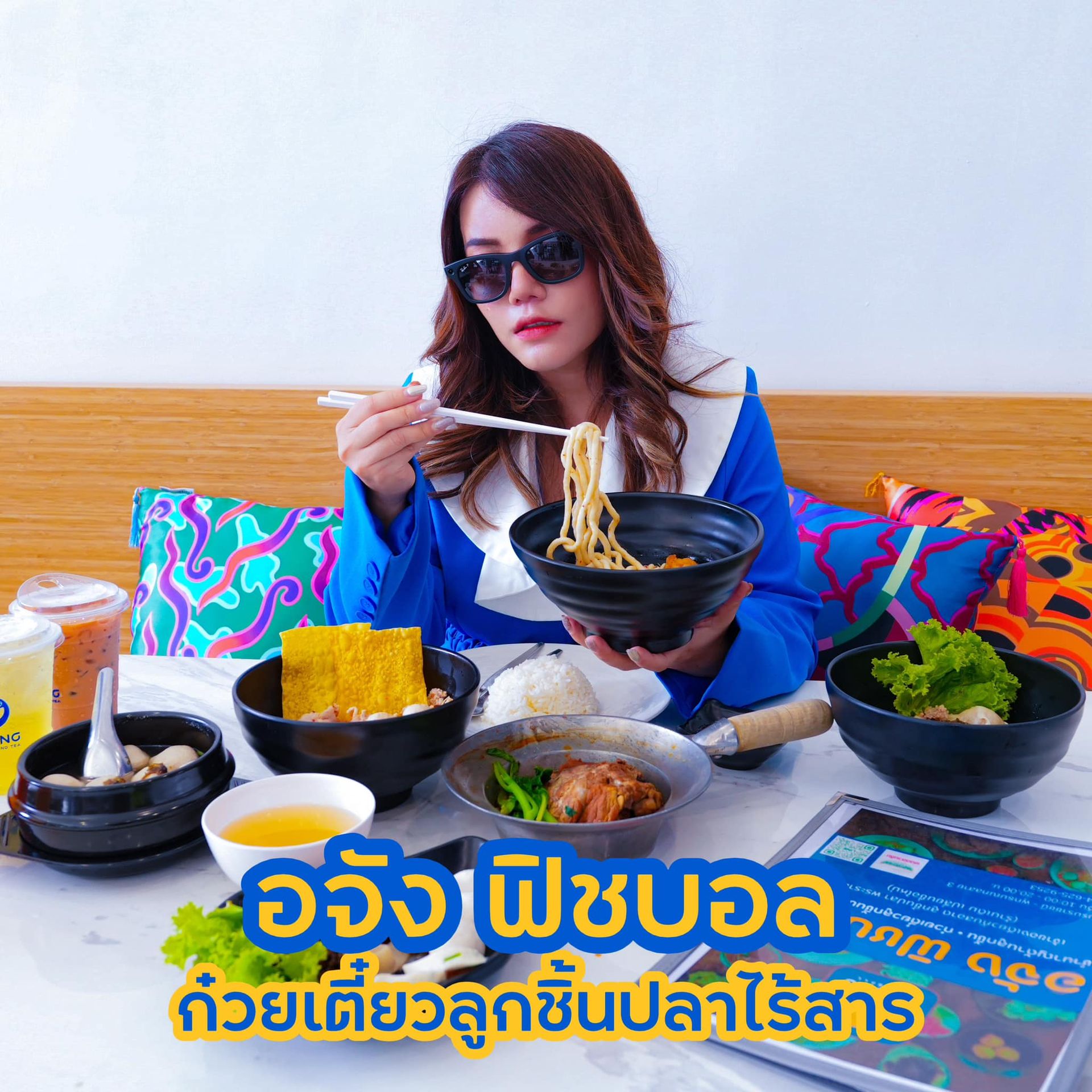 A woman is sitting at a table eating noodles with chopsticks.