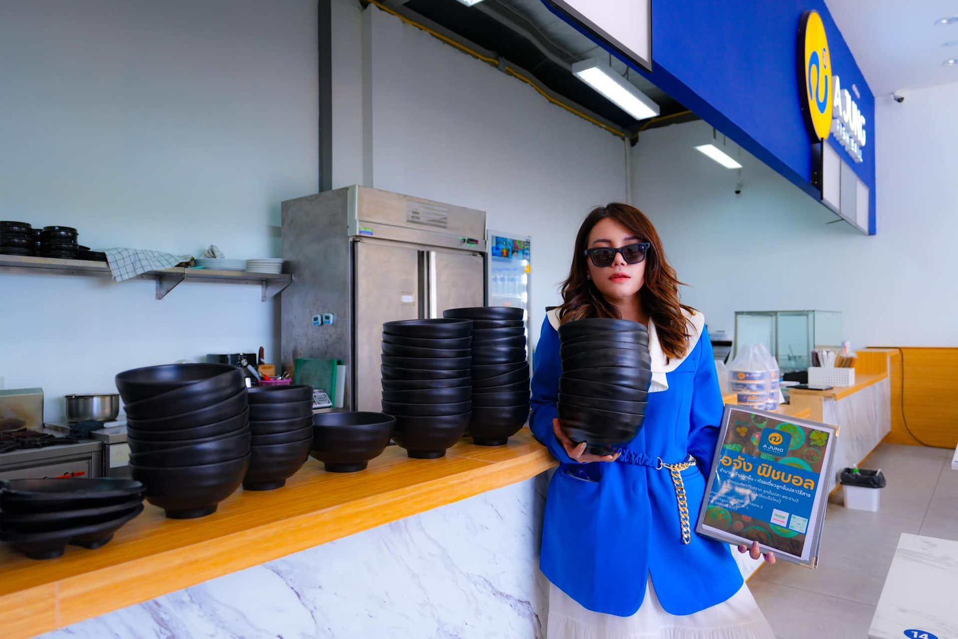 A woman in a blue jacket is holding a bowl in a 