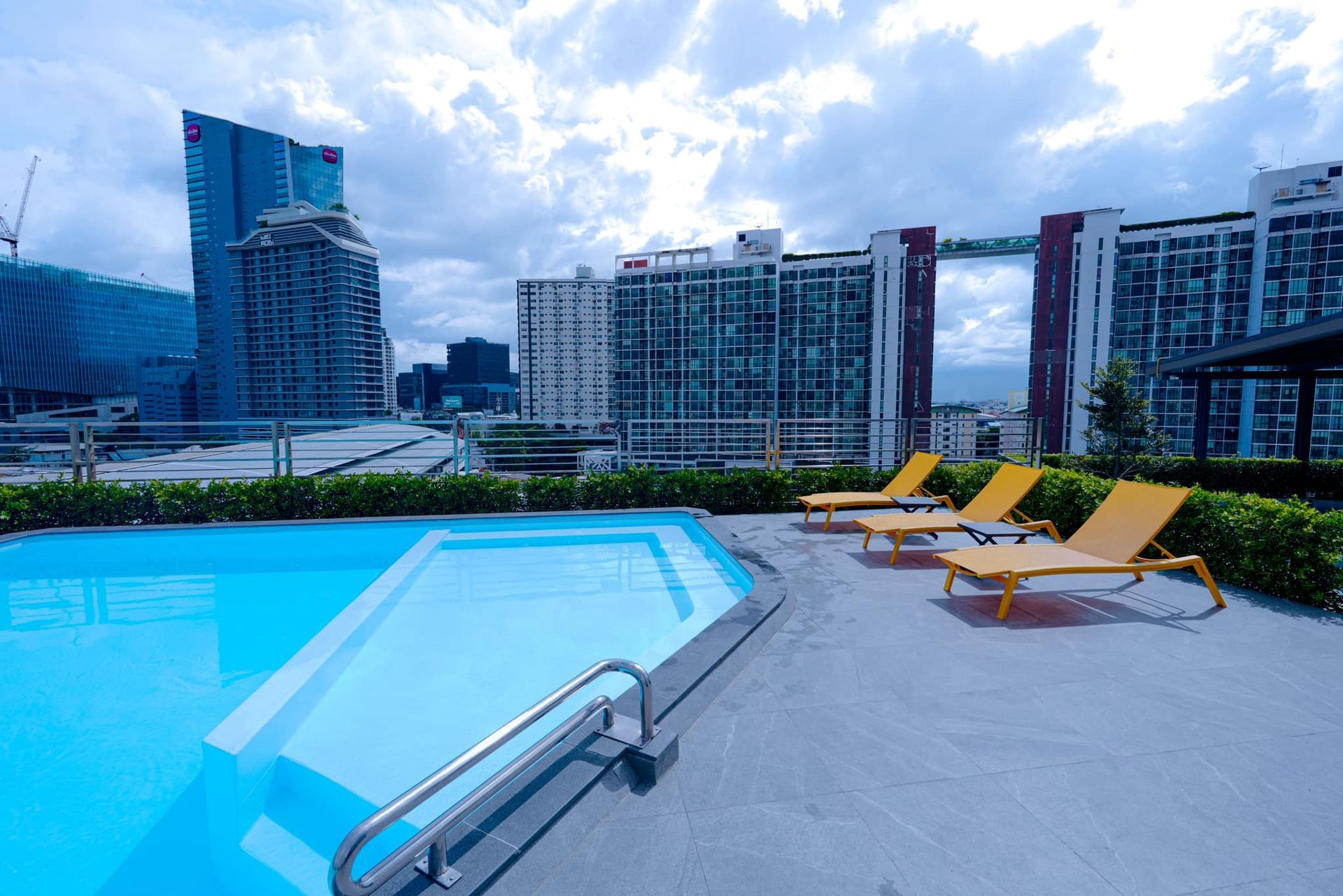 A swimming pool with chairs around it and a city in the background
