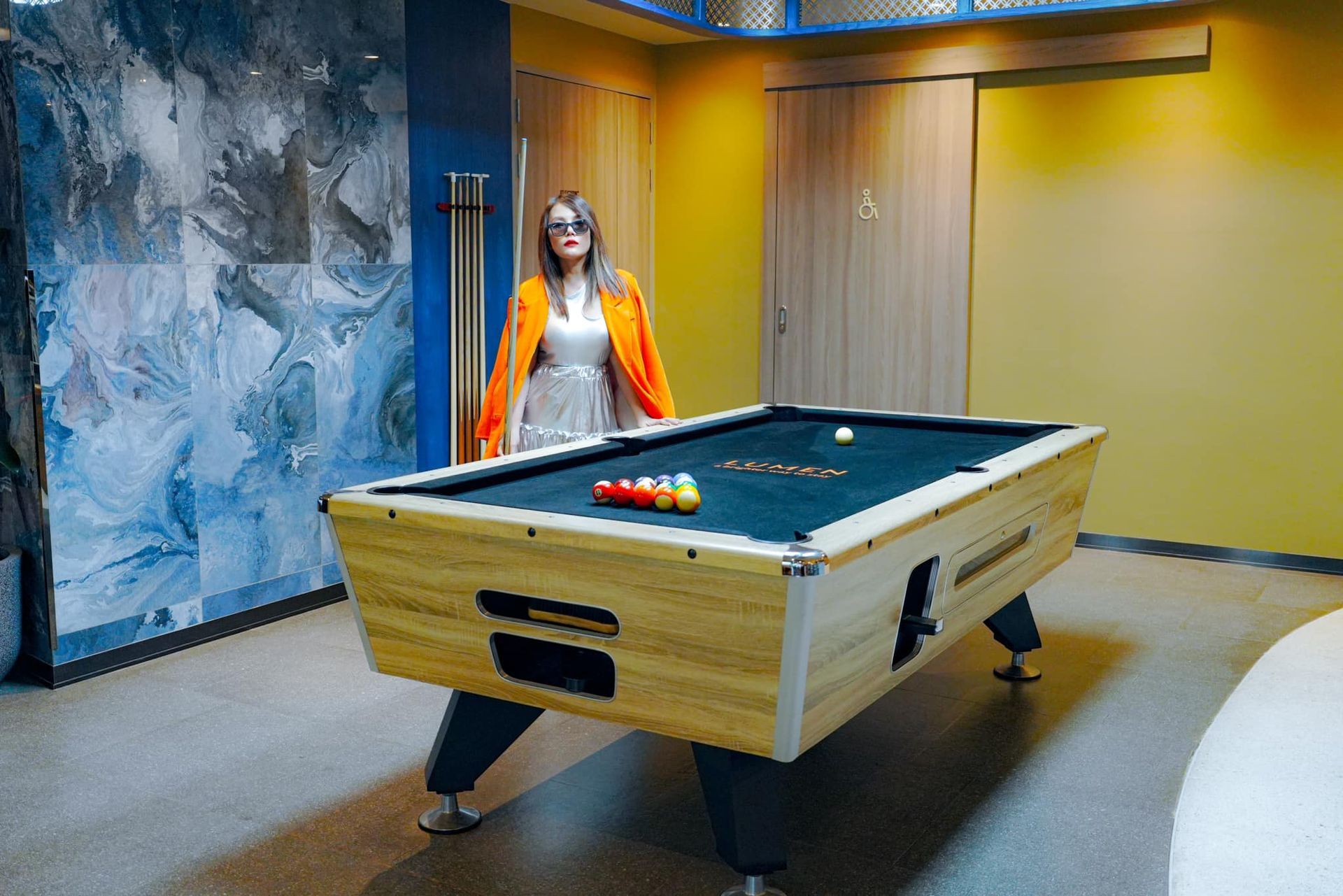 A woman is standing next to a pool table in a room.