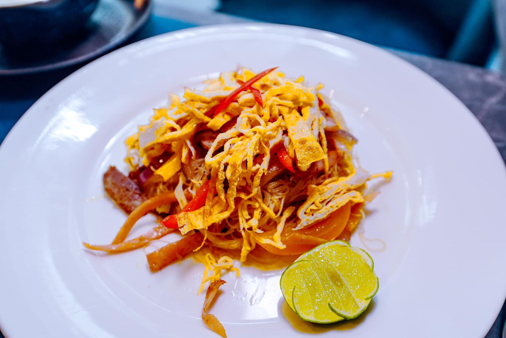 A close up of a plate of food with a slice of lime on a table.
