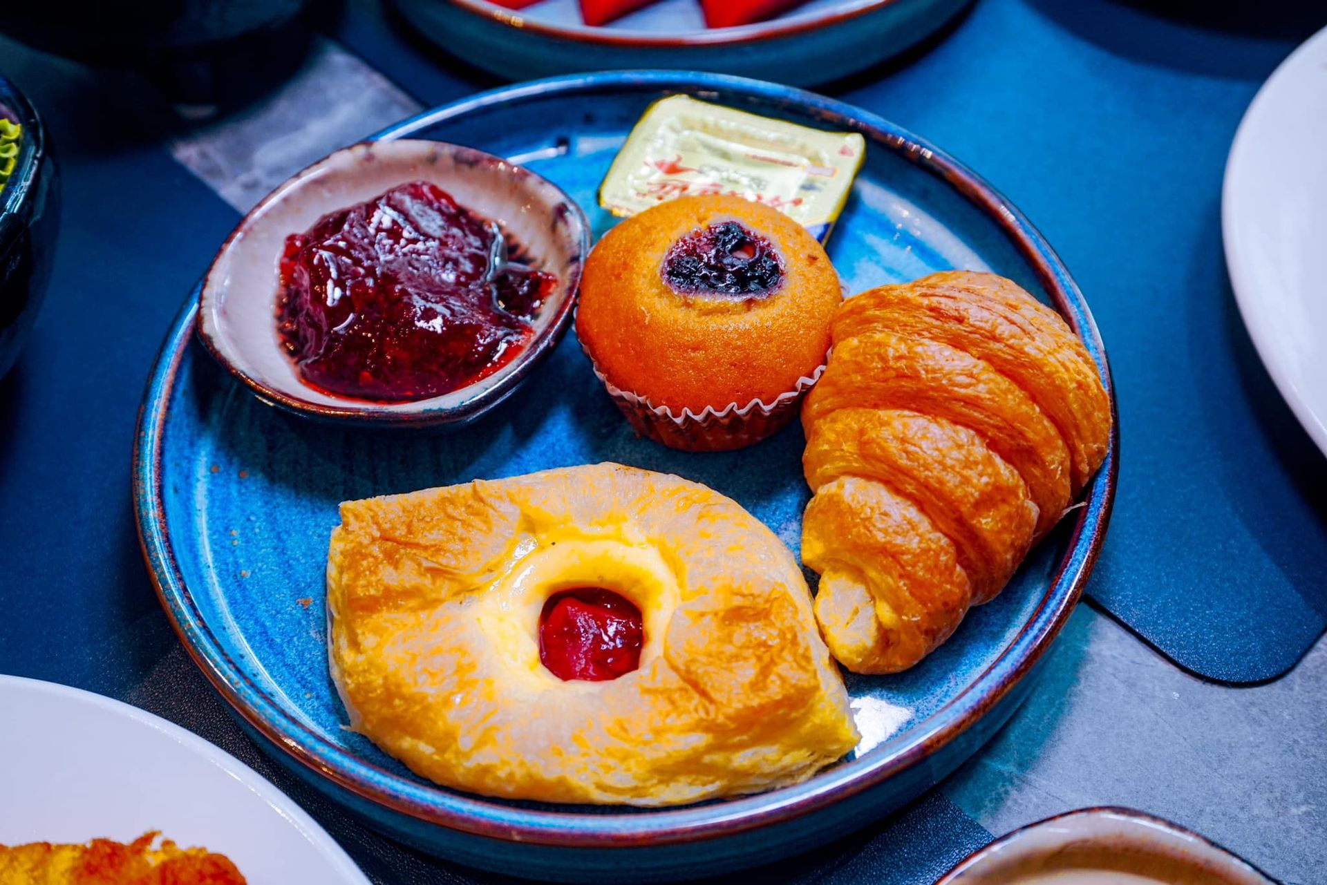 A blue plate topped with a variety of pastries and jam.
